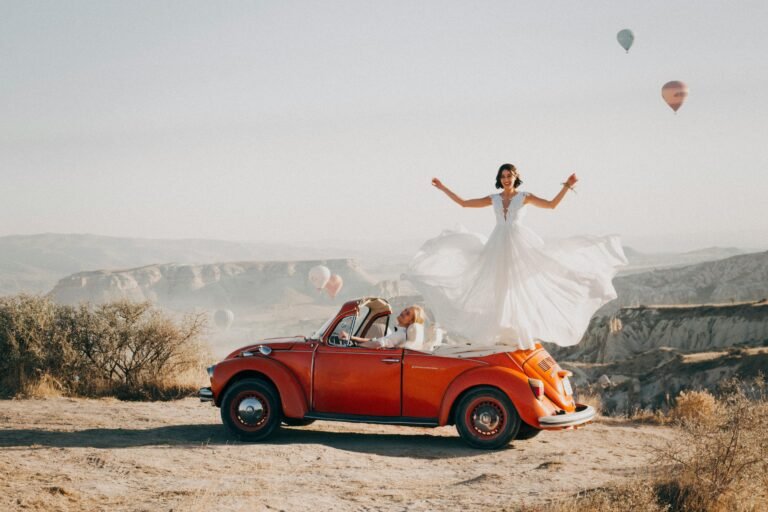 Bride and groom celebrating their wedding atop a vintage car in Cappadocia, Turkey.